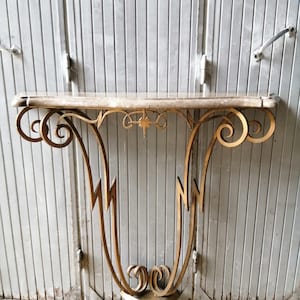 Peut inclure: Une console en métal doré avec un plateau en marbre. La table présente un design décoratif et orné avec un accent en forme d'étoile au centre.