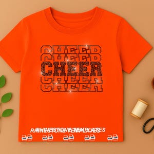 May include: A bright orange short-sleeved t-shirt featuring a central graphic design made of black rhinestones that spells the word CHEER in a bold, block font. The text RHINESTONE TEMPLATES is printed at the bottom with various file format icons.