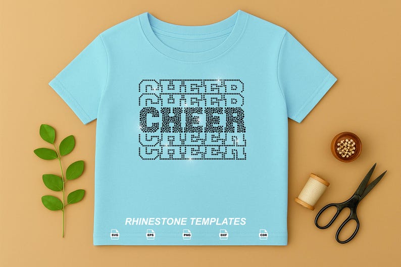 May include: A light blue short-sleeve t-shirt featuring a central graphic design made of black rhinestones that spells out the word CHEER in a repeating stacked pattern. The text RHINESTONE TEMPLATES is printed in white at the bottom of the shirt.