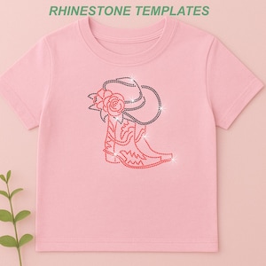 May include: A light pink t-shirt featuring a rhinestone design of a cowboy boot, hat, and rose. The boot and rose are red, while the hat and details are black. The text "RHINESTONE TEMPLATES" is at the top.