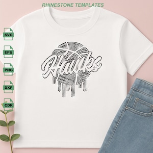May include: White t-shirt featuring a black rhinestone design of a basketball and the word "Hawks" in a script font. The design has a dripping effect. The shirt is paired with blue denim jeans.