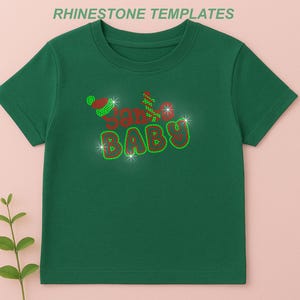 May include: Green t-shirt with the text "Santa Baby" in red and green rhinestones. The design includes a Santa hat and sparkling accents. The shirt is a festive apparel item, perfect for the holiday season.