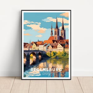 Può includere: Stampa artistica incorniciata di Ratisbona, Germania. L'opera raffigura un'illustrazione colorata dello skyline della città, tra cui un ponte, edifici con tetti rossi e alte guglie della chiesa. Il testo "Regensburg Germany" è in basso.
