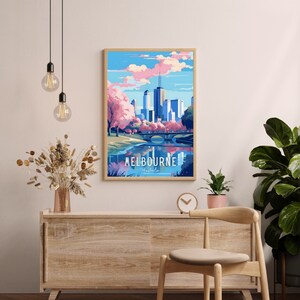 May include: A framed poster with a colorful illustration of the Melbourne skyline. The poster features a bridge over a river, trees, and a blue sky with pink clouds. The text "MELBOURNE Australia" is printed at the bottom of the poster.
