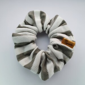 Scrunchie feito de tecido resistente com padrão de malha perfurada em cinza e branco