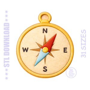 May include: A compass design with a gold-colored outer ring and a tan-colored face. The compass needle is red and light blue, with the cardinal directions labeled in black. The text "STL DOWNLOAD" and "31 SIZES" are visible.