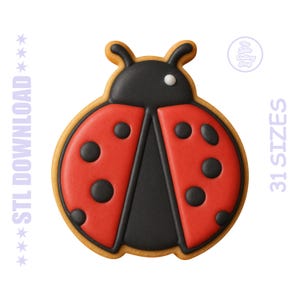 May include: A ladybug-shaped cookie cutter with a red body, black spots, and a black head. The cookie cutter has a light brown outline and the text "STL DOWNLOAD" and "31 SIZES" are visible.