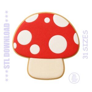 May include: A red mushroom-shaped cookie cutter with white polka dots and a beige stem. The cookie cutter has a brown outline. Text on the side reads "31 SIZES". The words "STL DOWNLOAD" are on the left side.