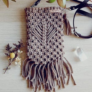 May include: A brown crocheted phone pouch with fringe. The pouch has a small leather tag that says "Moon Spirit Craft".