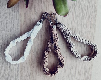 May include: Three crocheted keychains in white, beige, and brown. Each keychain has a silver metal clasp and a small round tag.
