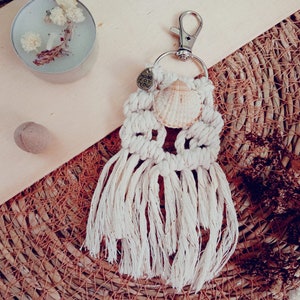 Op de afbeelding: Witte macramé sleutelhanger met een schelp en een zilveren bedel met de tekst "Made for You".