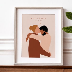 May include: A framed illustration of two people embracing. The couple is depicted in a minimalist style with brown and pink tones. The text "Will & Karim - 14.07.22" is printed below the illustration.