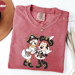 a red t-shirt with a cartoon image of Minnie Mouse and Donald Duck dressed as pirates, along with a necklace and a hat.