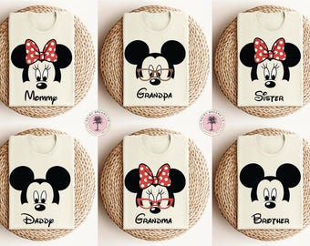 May include: Six white t-shirts with different family member titles printed on them. Each shirt features a cartoon image of Mickey Mouse or Minnie Mouse with different expressions. The titles are "Mommy", "Daddy", "Sister", "Brother", "Grandpa", and "Grandma".