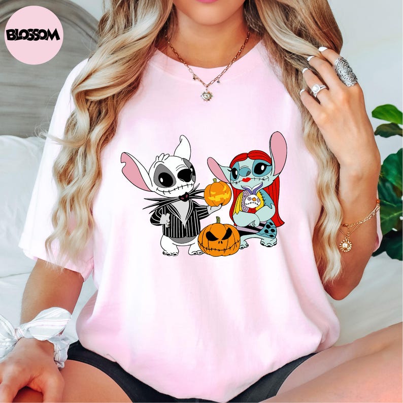 A woman wearing a pink t-shirt with a graphic of two cartoon characters from the movie "Jack Skellington and Sally" and a pumpkin.