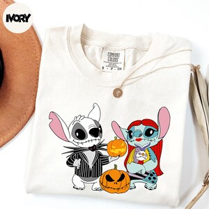 A white t-shirt with a graphic design featuring characters from the Disney movie " jack Skellington and Sally" and a pumpkin.