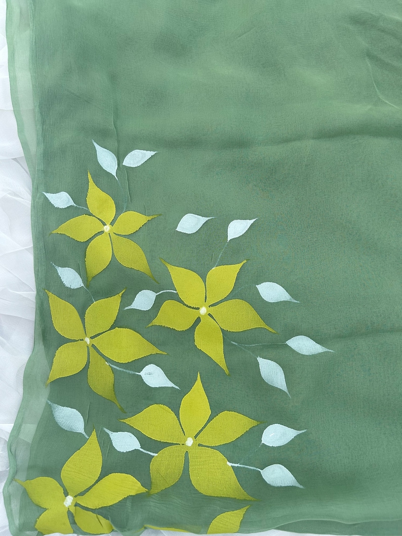 May include: A green fabric with a floral design. The flowers are yellow with white centers and are surrounded by white leaves.