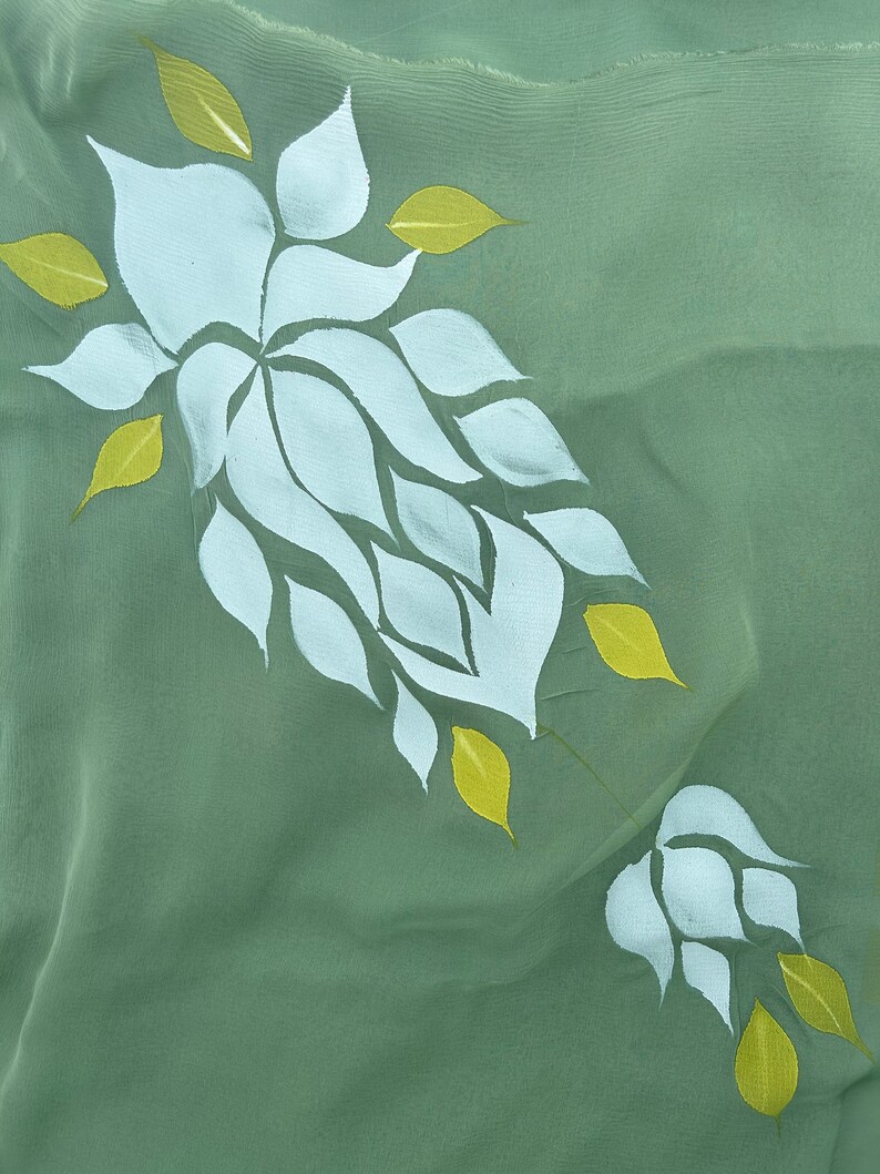 May include: A green fabric with a white floral design. The flowers are made up of multiple white petals with yellow leaves.