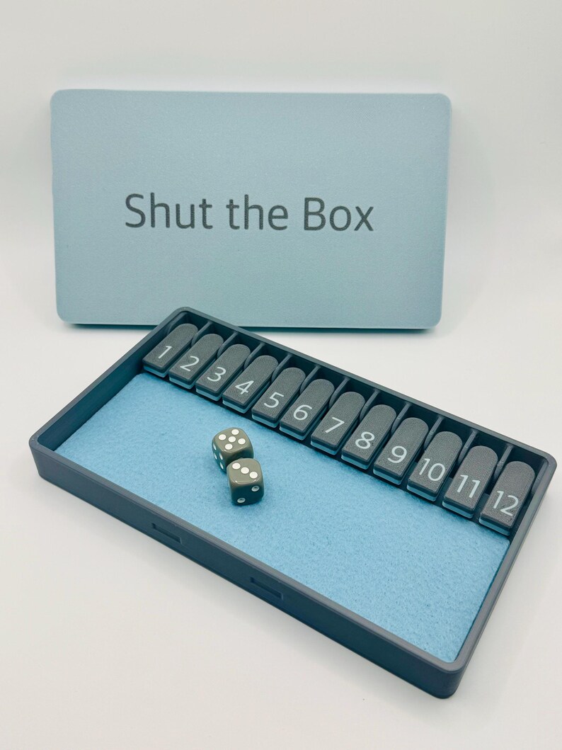 May include: A blue Shut the Box game with a gray tray and two gray dice. The tray has numbers 1 through 12.
