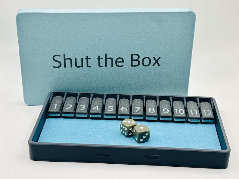 May include: A blue and black Shut the Box game with two dice. The game board has numbered tiles from 1 to 12.