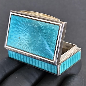 May include: A white ceramic mug with a black handle and the text "But First, Coffee" in a black, handwritten-style font. The mug is on a white surface.