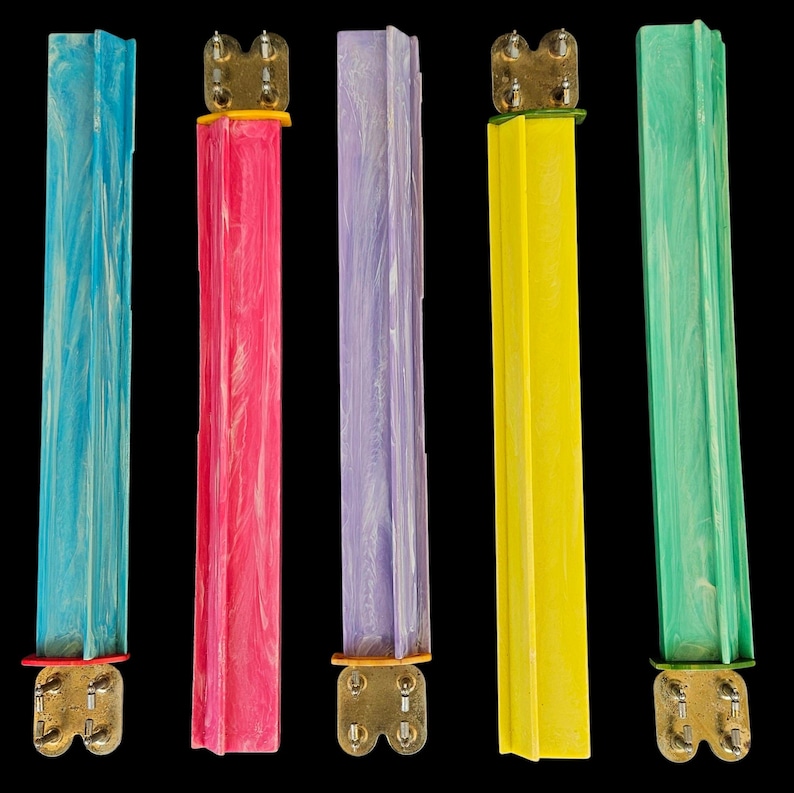 May include: Five vertical rectangular plastic components in blue, pink, lavender, yellow, and green, each featuring a marbled texture. Each piece is attached to a metallic base with four small prongs, providing a distinct structural contrast.