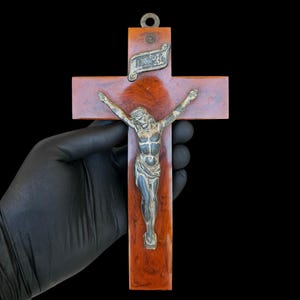 May include: A wall crucifix featuring a polished, marbled reddish-brown cross with a metallic silver-toned figure of Jesus attached to the center. Above the figure is a small, rectangular silver-toned plaque with the engraved letters INRI.