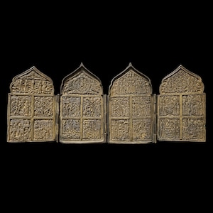 Pode incluir: Um ícone religioso antigo de quatro painéis com entalhes em relevo intrincados. Os painéis articulados apresentam cenas de histórias religiosas. O ícone é feito de um metal dourado e está sobre um fundo preto.