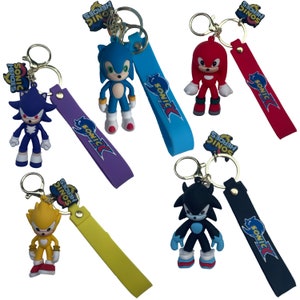 May include: Set of six Sonic the Hedgehog keychains featuring different characters from the video game series. Each keychain has a colorful character charm and a matching strap with the Sonic logo. The characters include Sonic, Shadow, Knuckles, Tails, Amy, and Metal Sonic.