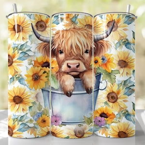 May include: A set of three stainless steel tumblers with a design of a Highland cow in a bucket of sunflowers. The tumblers are white with a floral pattern.