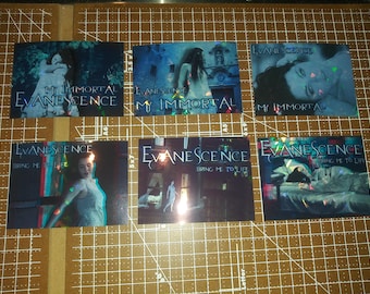 May include: Six holographic trading cards featuring the band Evanescence. The cards feature different album covers and song titles, including "My Immortal" and "Bring Me To Life".