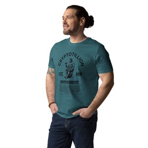 May include: A teal blue t-shirt with a black graphic print of a man sitting on a throne. The graphic includes the text "Cryptotillion Est. 1991 Cryptocurrency".