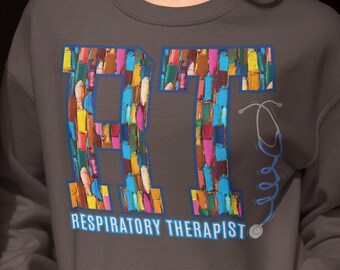 Może przedstawiać: Szara bluza z kapturem z literami RT w kolorowych pociągnięciach farby i tekstem "Respiratory Therapist" poniżej. Niebieski stetoskop jest narysowany obok liter.