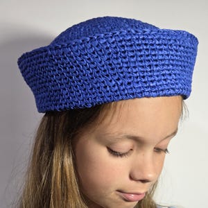May include: A vibrant blue woven hat with a rounded crown and a slightly upturned brim. The hat is made of a textured material and is a bright, eye-catching accessory. The hat is a stylish head covering.