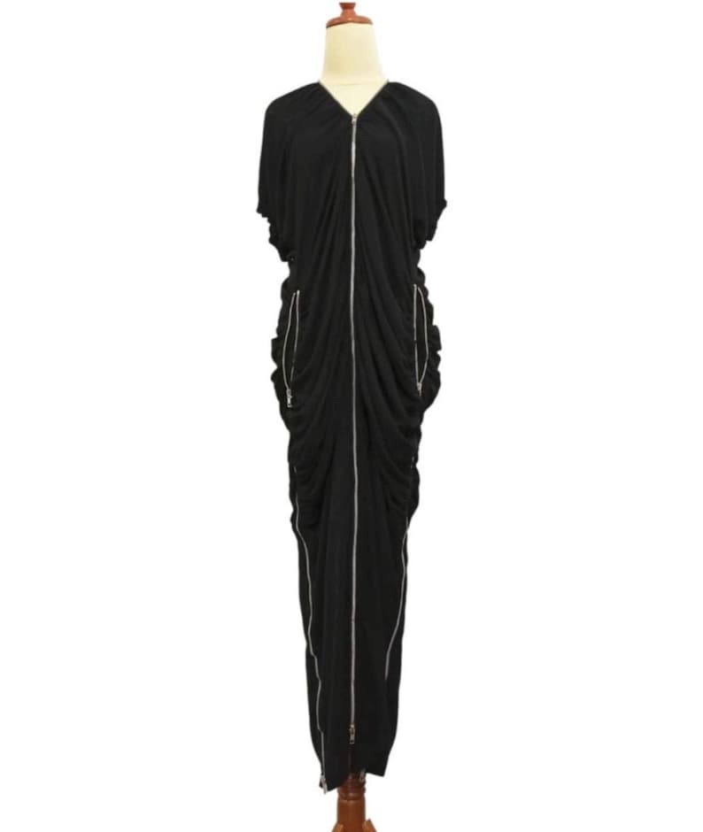 May include: A black maxi dress with a V-neckline and short sleeves. The dress features a full-length silver zipper down the front and two side zippers. The fabric is draped and ruched, creating a flowing silhouette.