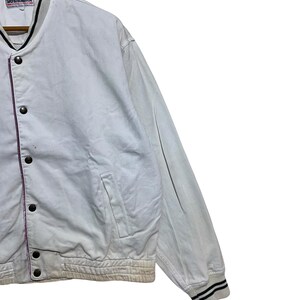 May include: White vintage jacket with black and white striped cuffs. The jacket has a button-up front, a pocket, and a black collar. The brand name "Yoshimura" is visible on the label.