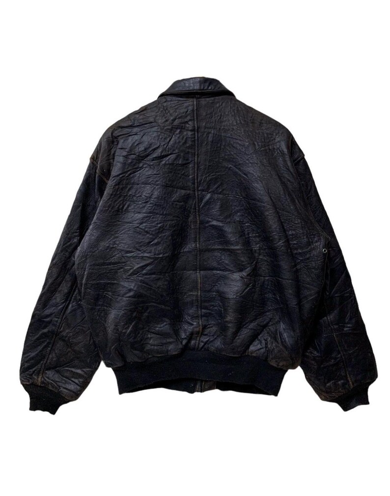 May include: A vintage black leather bomber jacket with a ribbed collar, cuffs, and hem. The jacket has a classic design with a slightly distressed appearance, suggesting it's been well-worn. The back view shows the full shape and texture of the leather.