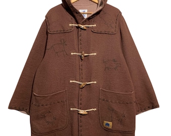 Könnte beinhalten: Ein brauner Dufflecoat mit Kapuze und Knebelverschlüssen aus Holz. Der Mantel hat zwei Vordertaschen und gestickte Details. Ein kleiner blau-gelber Aufnäher befindet sich auf der unteren rechten Tasche.