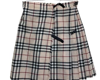 May include: A beige plaid skirt with black, white, and red lines. The skirt has a pleated design, a black belt, and buckle details. The skirt is hanging on a wooden and metal hanger.