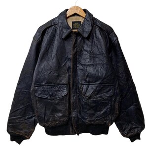 May include: A vintage black leather bomber jacket with a collared neckline, two front pockets, and a ribbed hem and cuffs. The jacket is hanging on a wooden hanger against a white background. The leather has a distressed appearance.