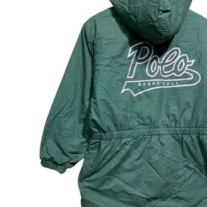 Pu&ograve; includere: Giacca con cappuccio verde con la scritta "Polo BASKETBALL" in bianco. La giacca ha una vita con coulisse e polsini elasticizzati. La giacca &egrave; realizzata in materiale trapuntato.