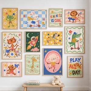 Puede incluir: Una pared de galería con doce láminas de arte enmarcadas que muestran ilustraciones coloridas de animales como una rana, conejo, león, tigre, oso, jirafa, cebra, cocodrilo y oveja, con el texto Kindness Is Cool y Play All Day.
