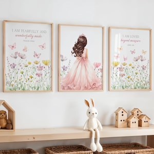 May include: Three framed art prints with inspirational quotes and floral and butterfly illustrations. A watercolor image of a girl in a pink dress is in the center. A wooden shelf holds a teddy bear, a stuffed bunny, and wooden houses.