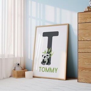 May include: A framed print with a black letter T and a panda bear illustration. The name Tommy is written below the letter.