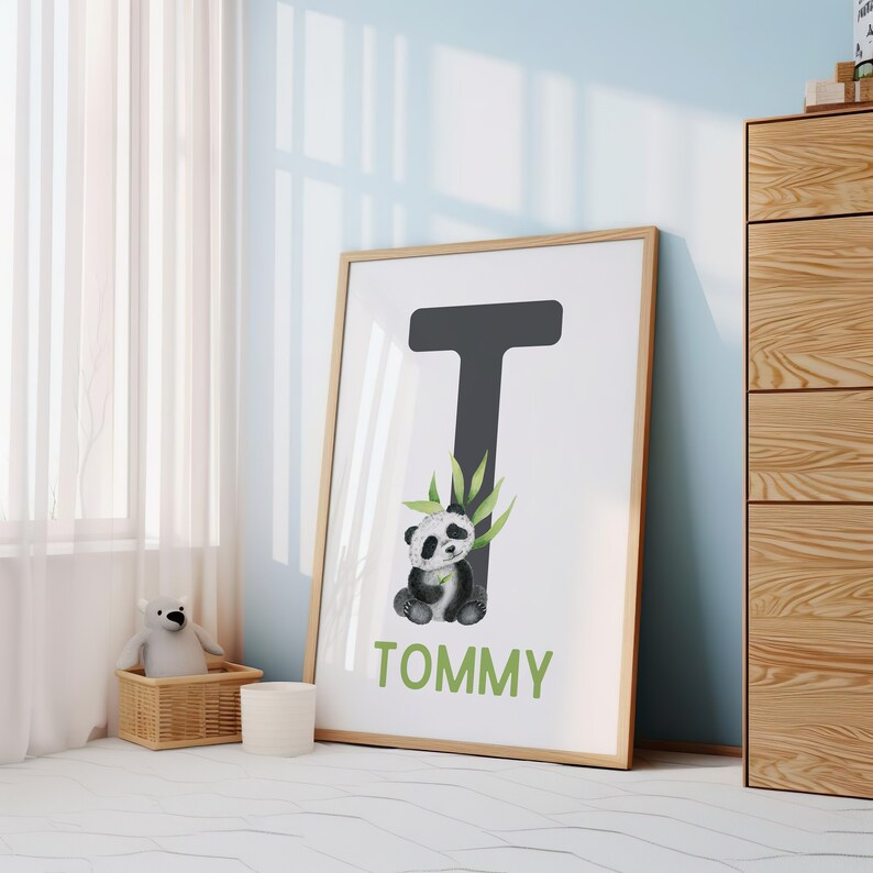 May include: A framed print with a black letter T and a panda bear illustration. The name Tommy is written below the letter.
