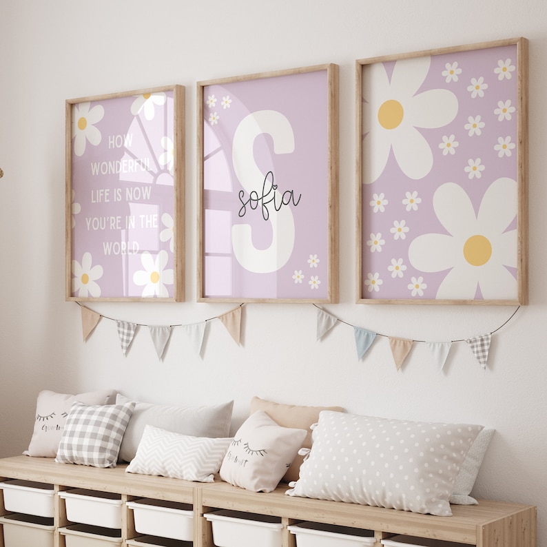 May include: Three framed prints with a purple background and white daisy designs. The center print features the name "sofia" in white lettering. The left print features the text "How wonderful life is now you're in the world". The right print features a larger daisy design.