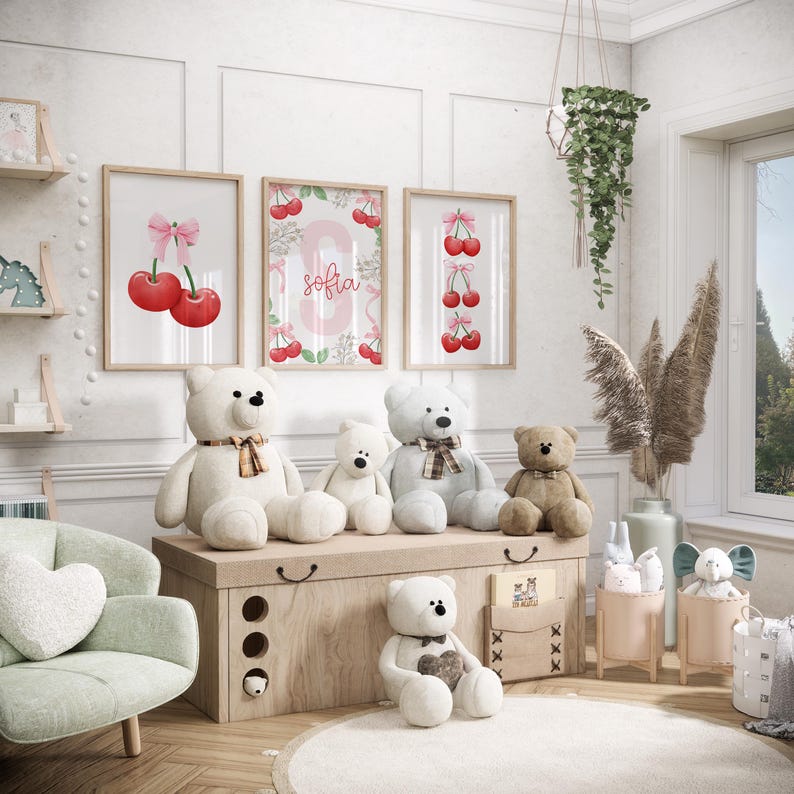 May include: A nursery room with a white chest of drawers, four teddy bears, and three framed prints with pink bows and cherries. The prints feature the name "Sofia" on one of them.