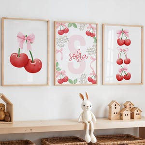 May include: Three pink and white framed prints with watercolor illustrations of cherries and a pink letter S with the name "sofia" written in red.