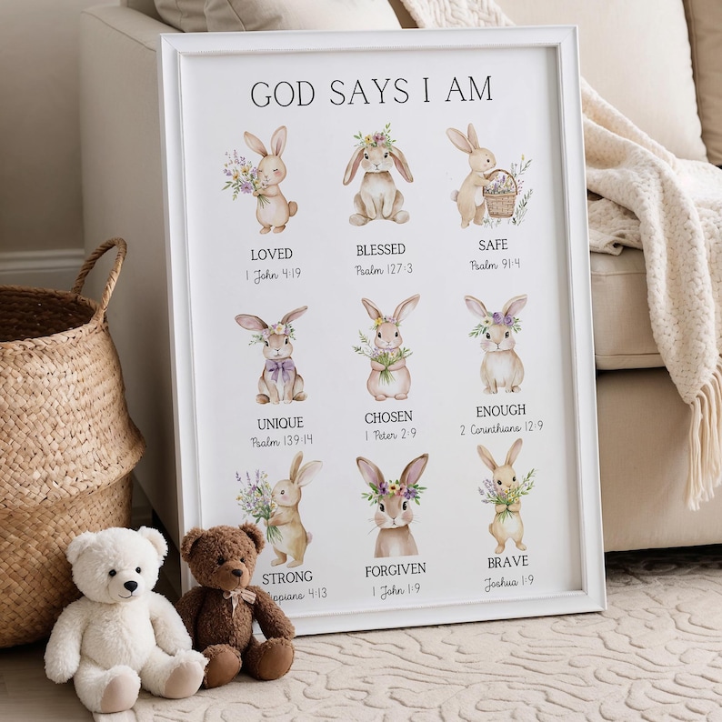 May include: White framed art print with the text "GOD SAYS I AM" and illustrations of bunnies with floral accents. The print includes the words "LOVED", "BLESSED", "SAFE", "UNIQUE", "CHOSEN", "ENOUGH", "STRONG", "FORGIVEN", and "BRAVE".