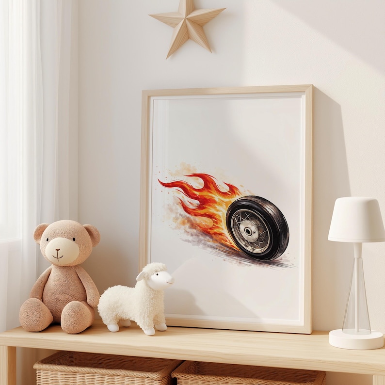 May include: Framed artwork featuring a black tire with flames, set against a white background. The artwork is in a light wooden frame. A teddy bear, a lamb, and a lamp are on a wooden shelf below the artwork.